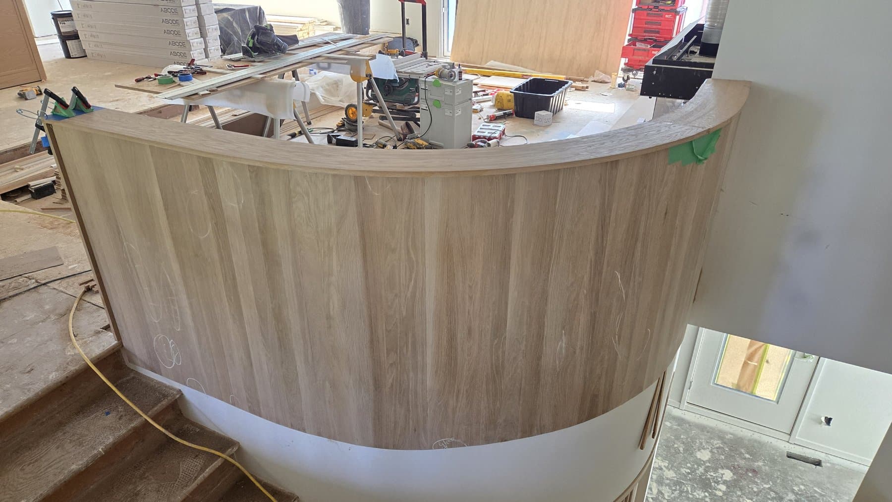Curved oak-paneled counter under construction with vertical slat cladding