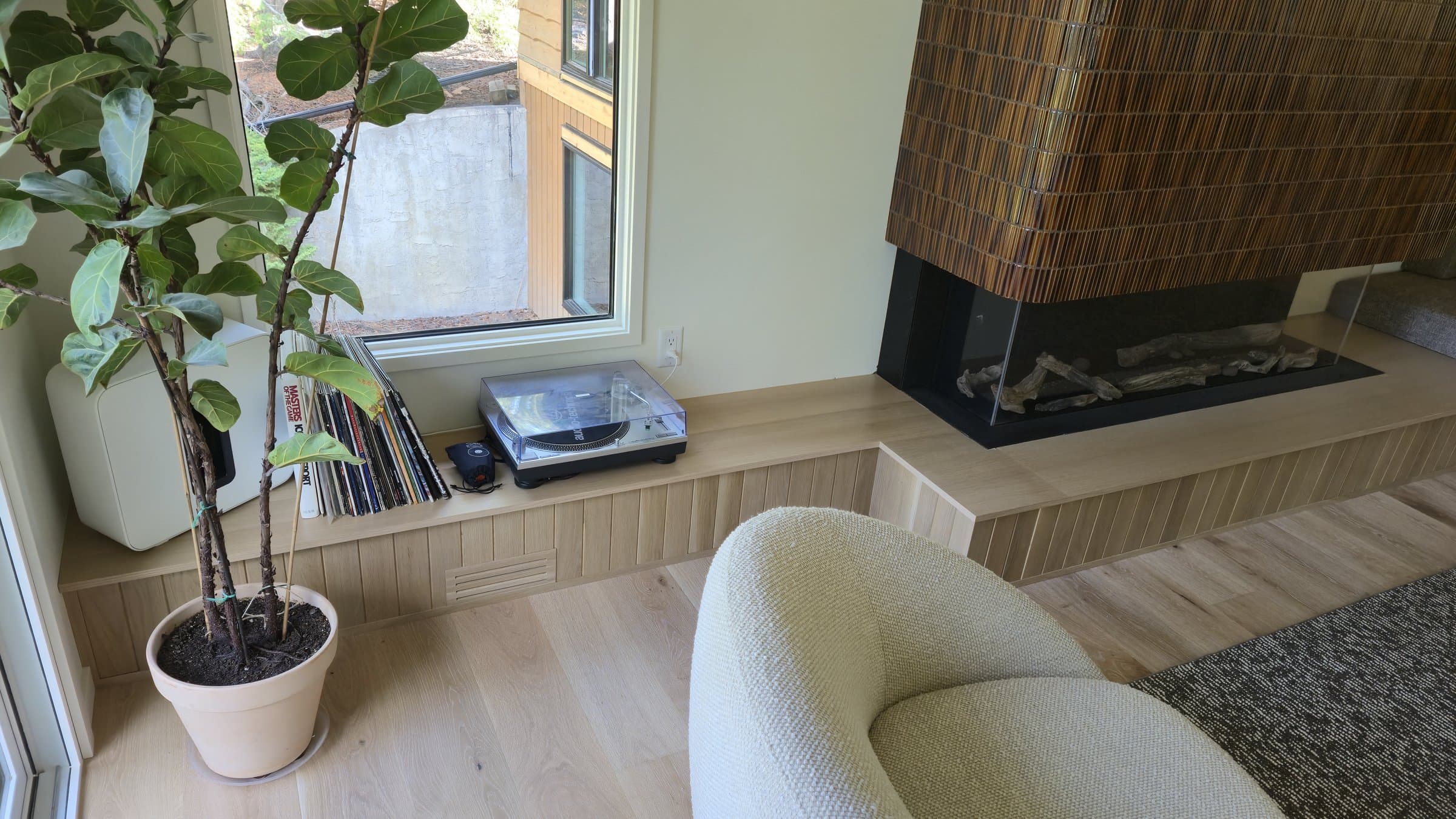 Built-in curved banquette bench beside a textured-tile fireplace column