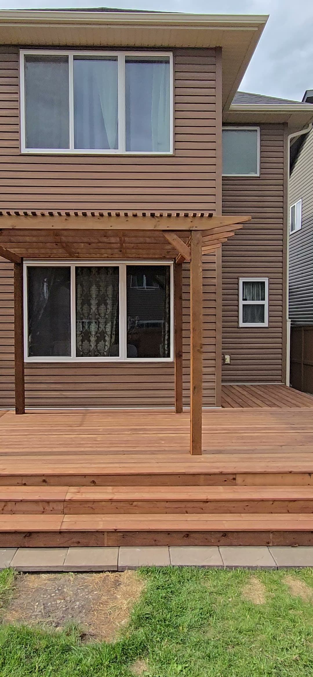 Finished cedar pergola over a deck attached to a two-story home