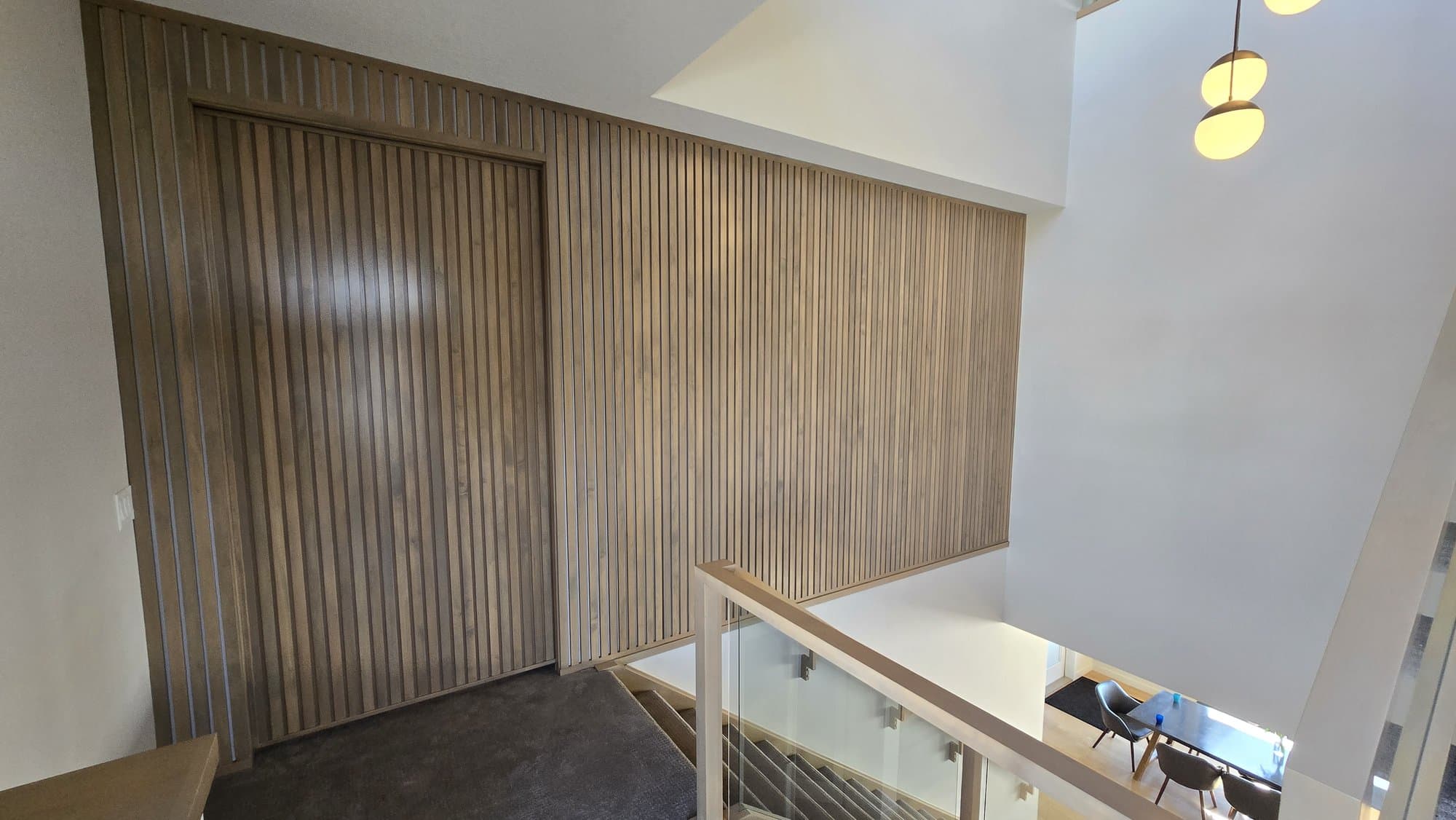 Wood slat sliding closet door matching a stairwell accent wall