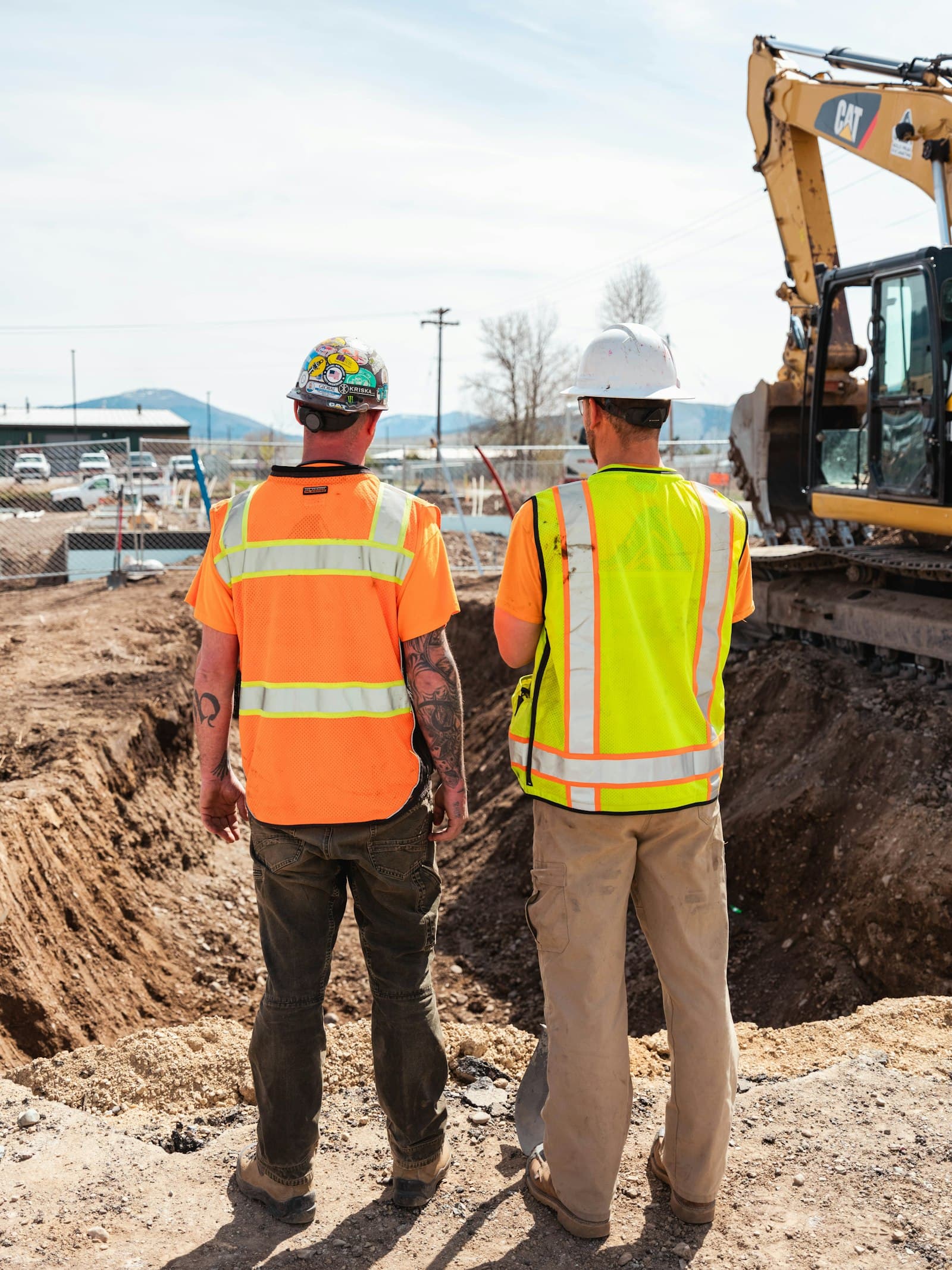 Two construction workers in safety gear overseeing a job site